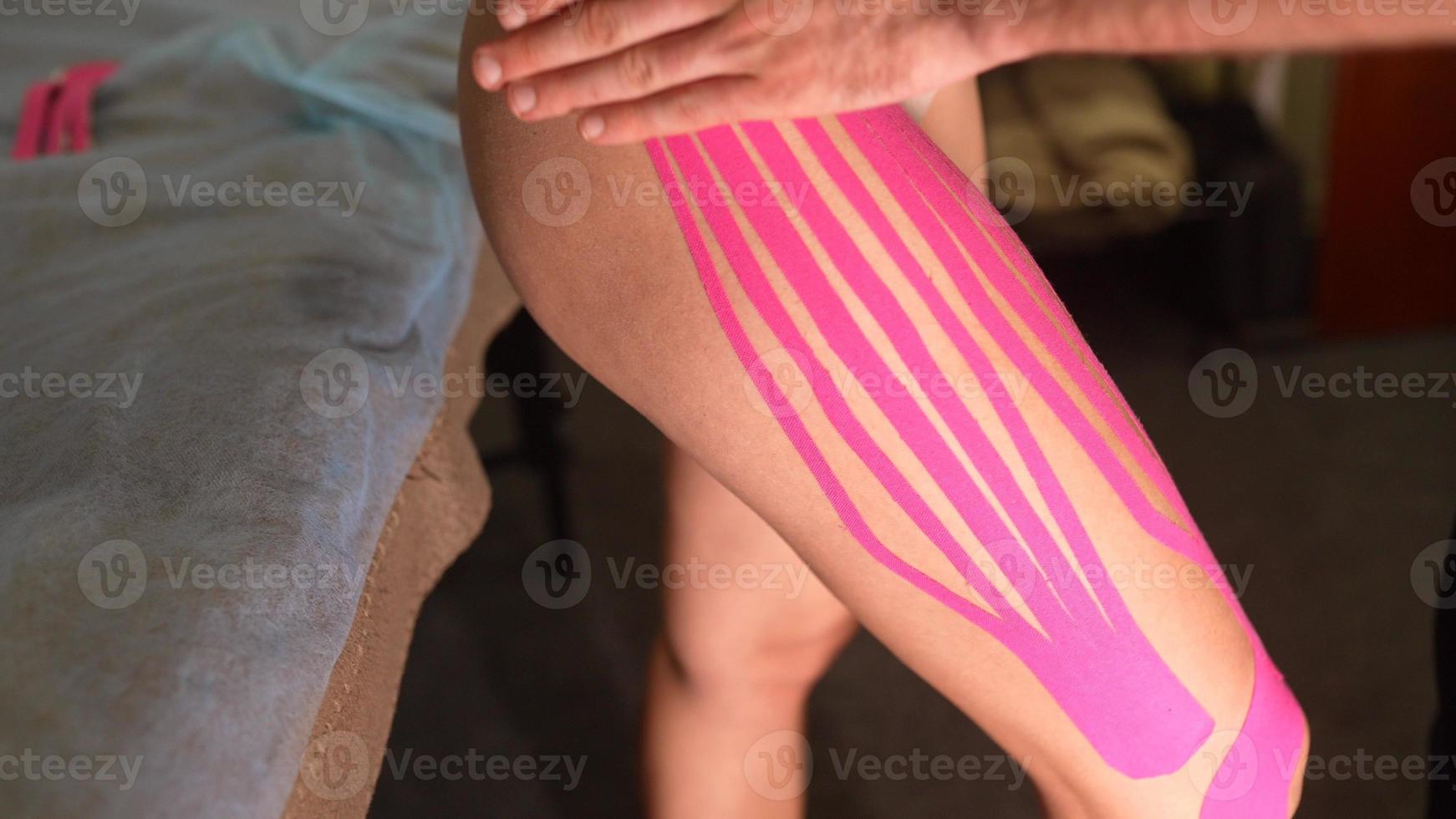 fisioterapeuta aplicando cinta kinesio en paciente femenino. foto