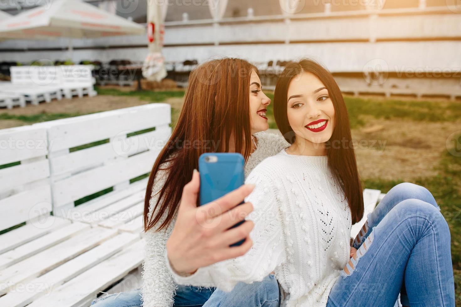 Two girls making selfie on the bench photo