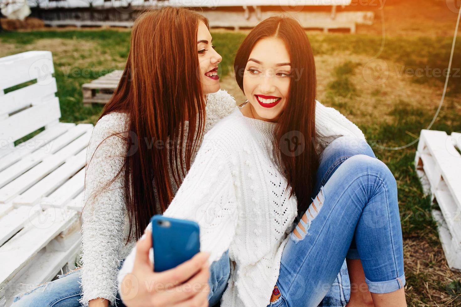 Two girls making selfie on the bench photo