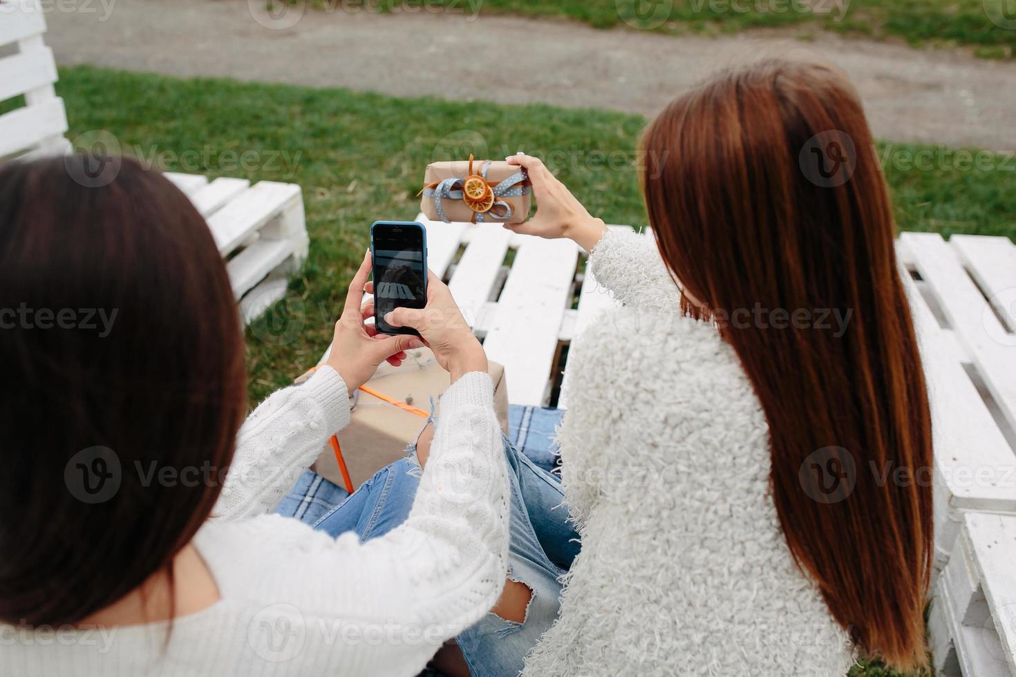 Girls sit on a bench and shoot gifts photo