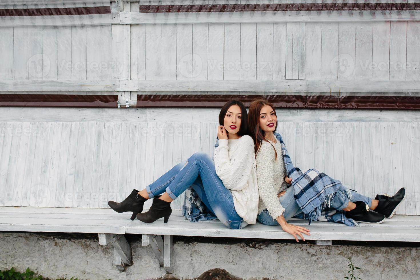 Two girls sit on a bench in the park photo