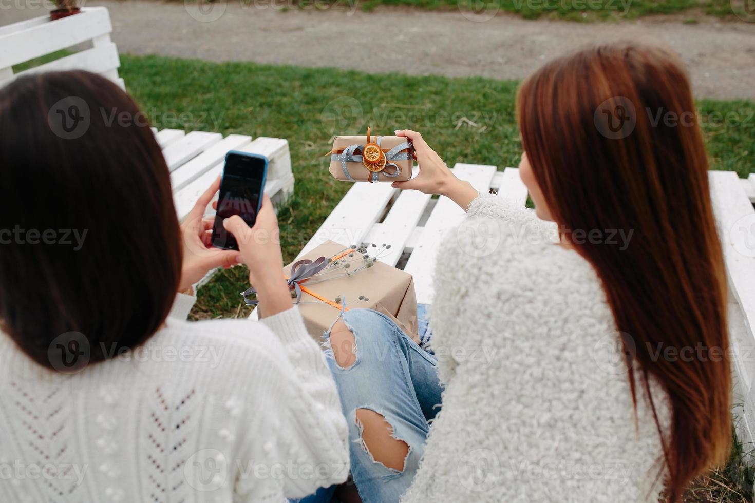 Girls sit on a bench and shoot gifts photo