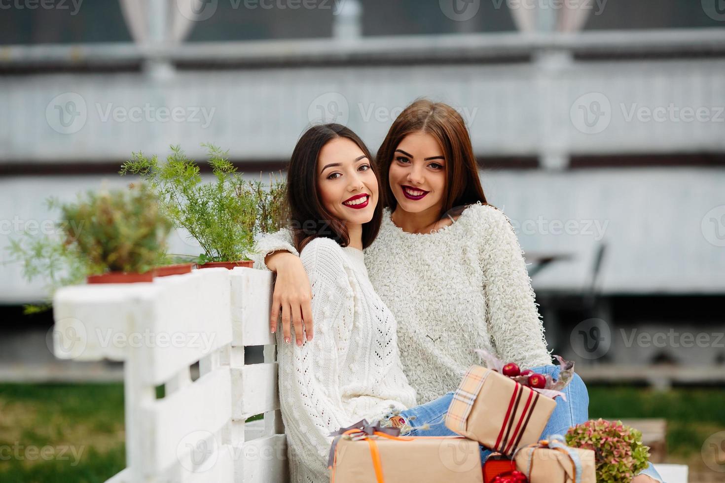 Two beautiful girls sitting on a bench photo