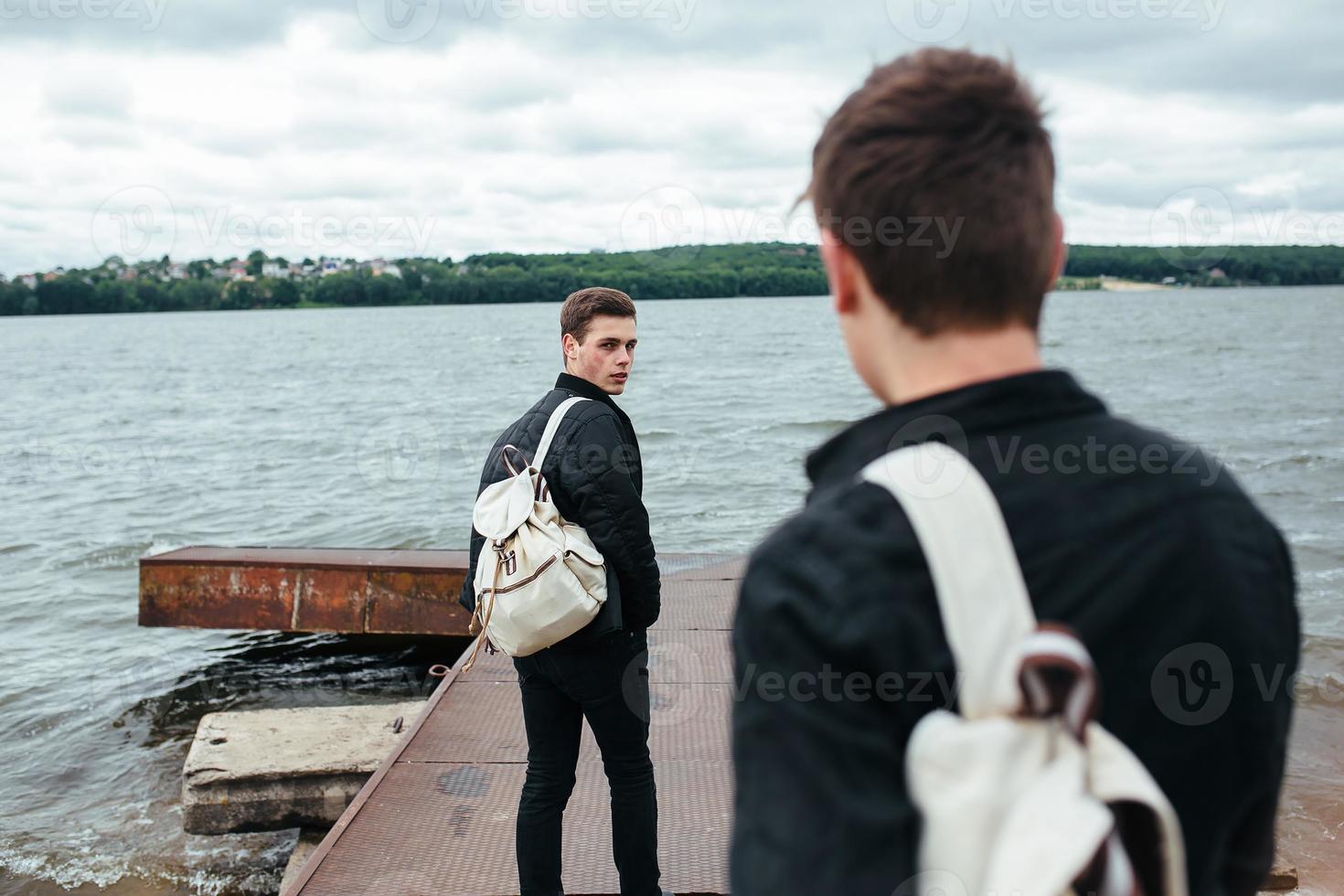 two young guys standing on a pier photo