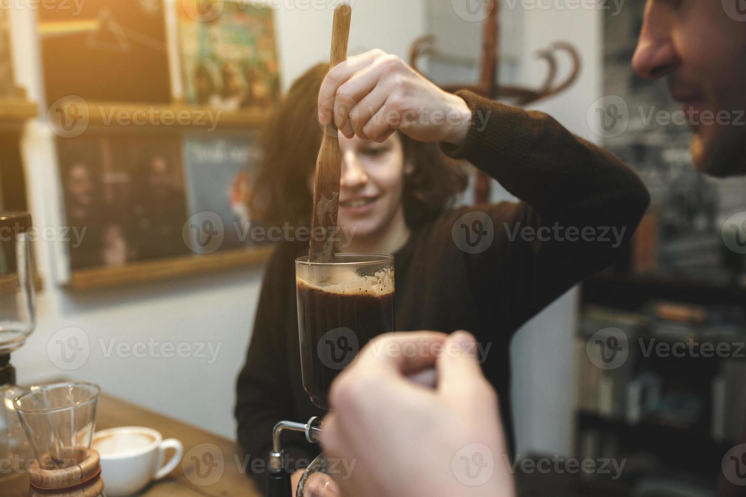 Vintage couple preparing coffee with vacuum coffee maker.Coffee shop photo