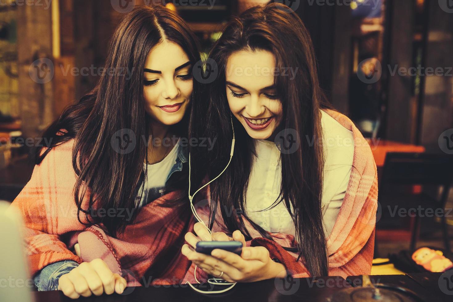 Two girl sitting listening to music with a smartphone photo