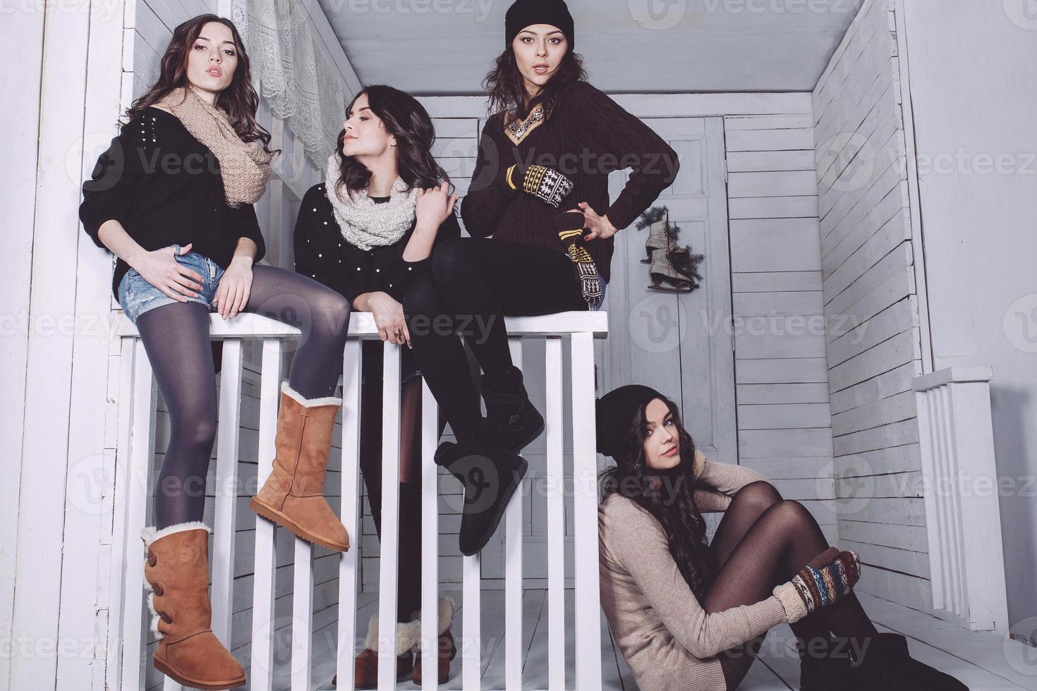 Four stylish models posing sitting on the fence. Christmas background photo