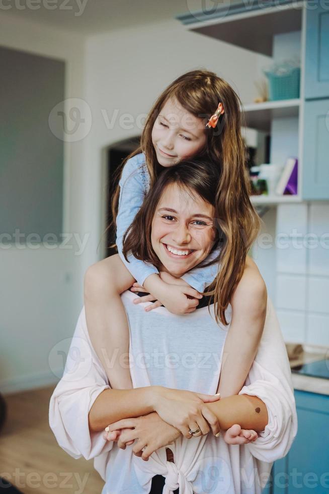 beautiful little daughter piggybacking on her happy mother photo