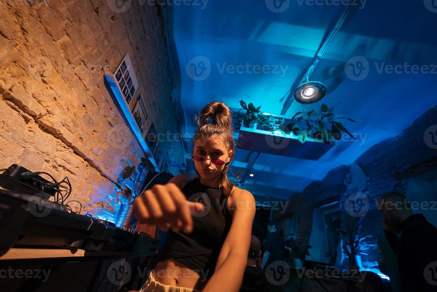 Beautiful female DJ dancing to techno in a small club photo