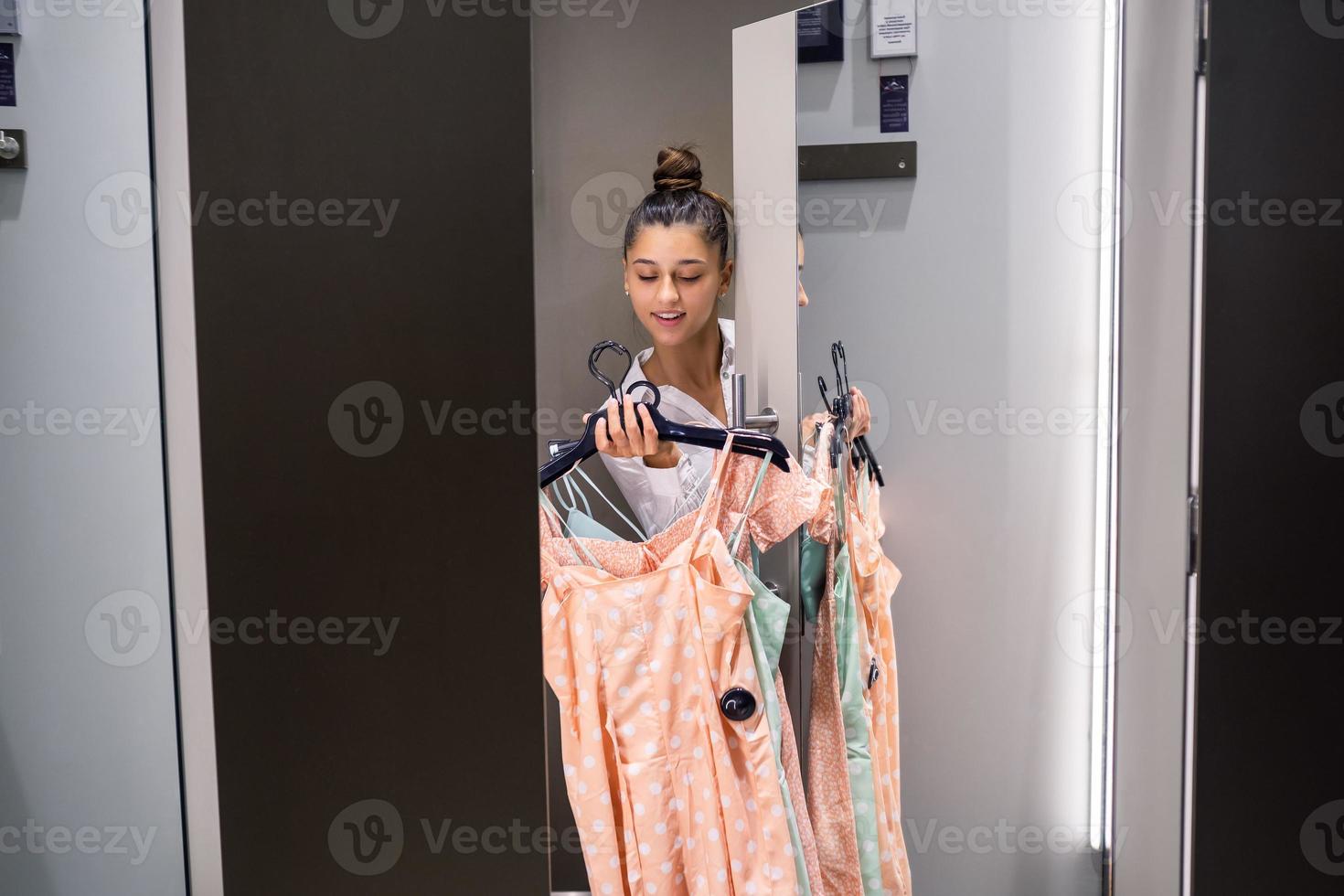 Beautiful girl with lots clothes in room background in a boutique photo