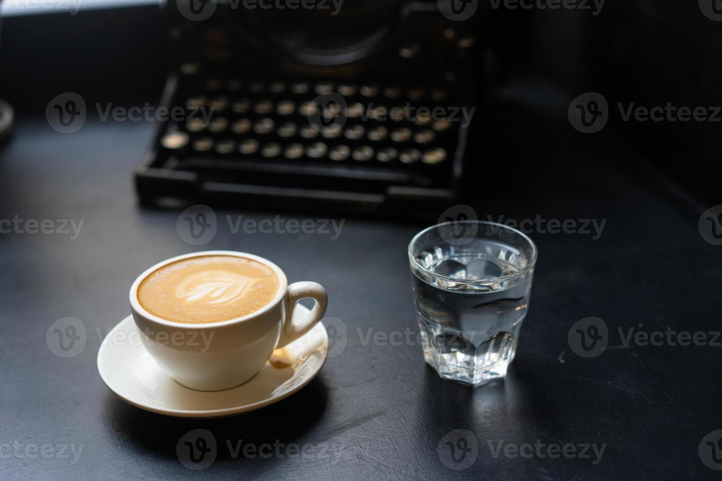 A cup of cafe latte coffee in a ceramic cup and a glass of water photo