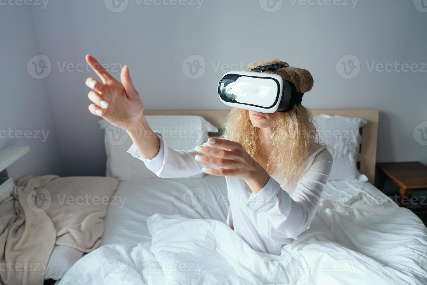 Girl sitting on a bed with VR headset photo