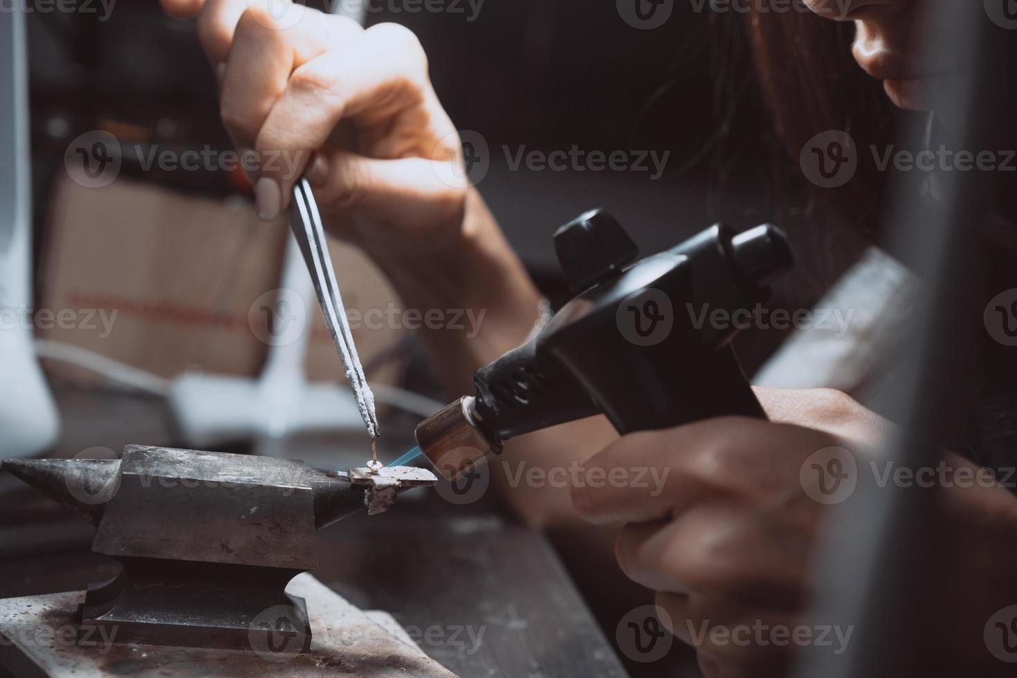 en el taller, una mujer joyera está ocupada soldando joyas foto