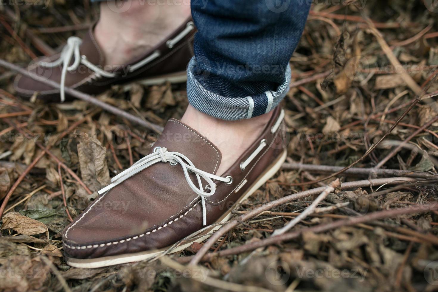 Feet of the man in the authentic boots and  selvedge jeans,on the background of branches photo