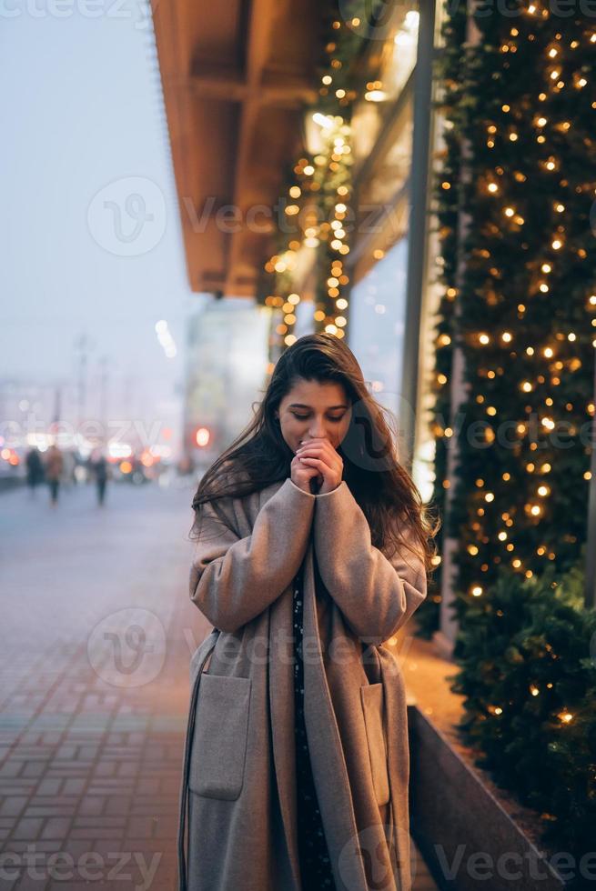 mujer por escaparate iluminado en la calle de la ciudad. foto