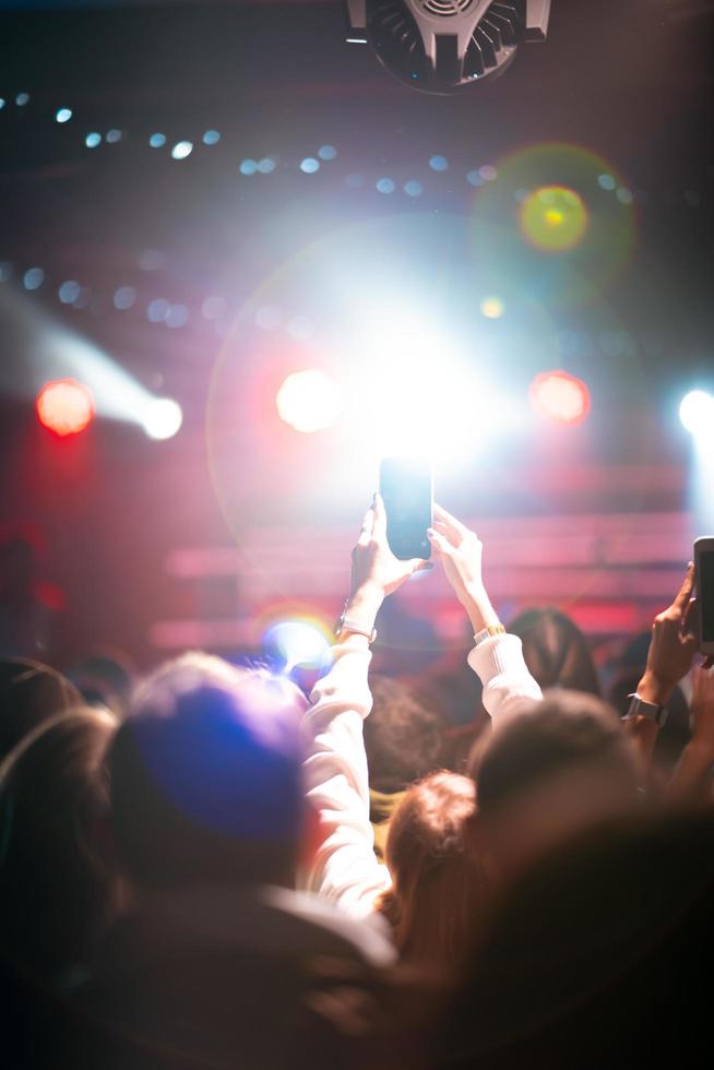 Person close up of recording video with smartphone during a concert. photo