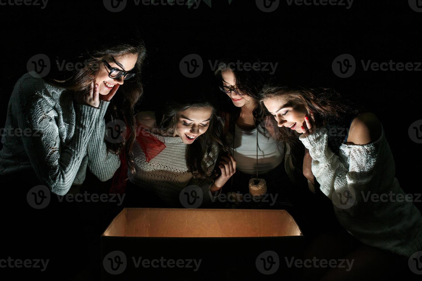 Sisters opens a box with a Christmas present and fascinated looks inside photo