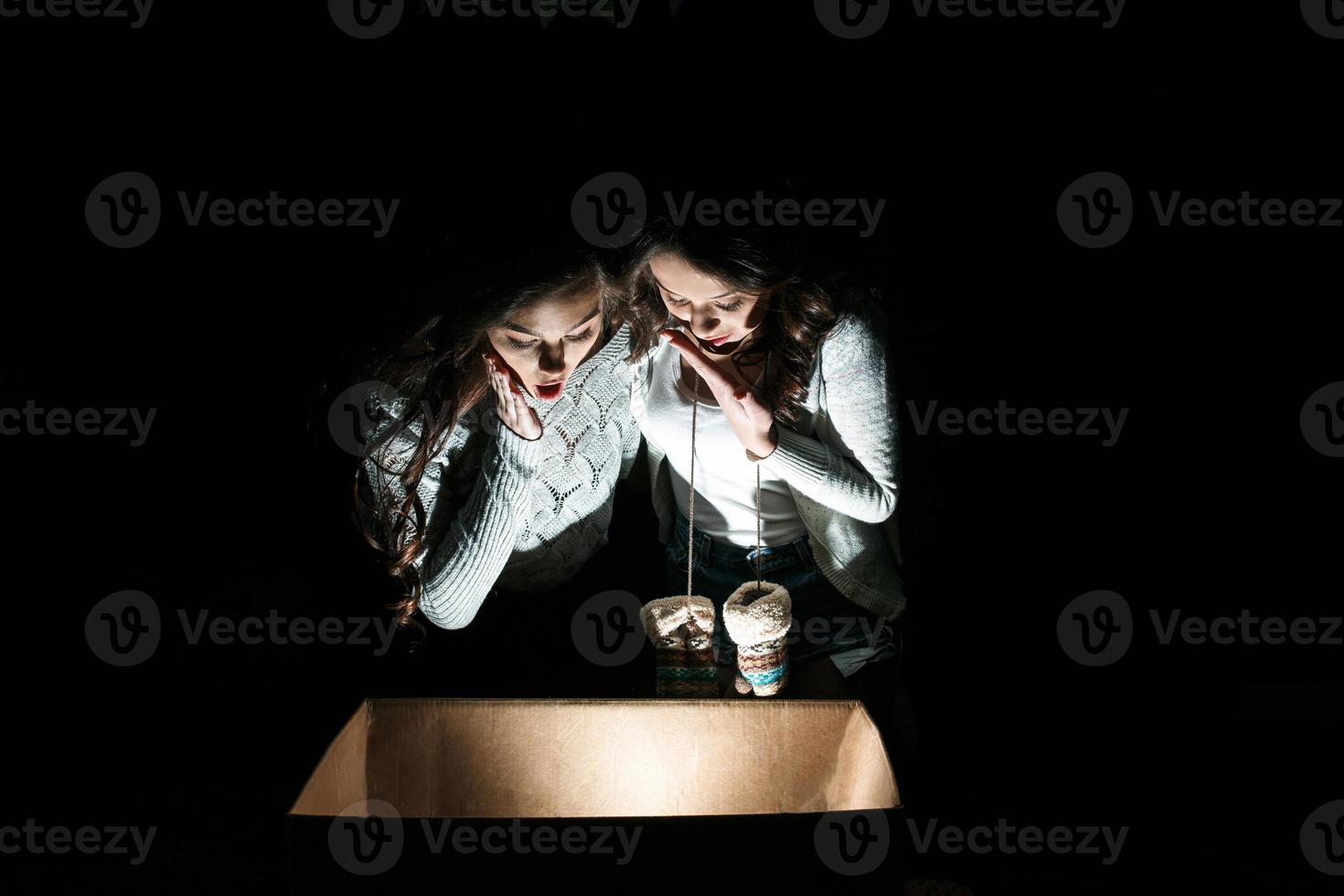 Sisters opens a box with a Christmas present and fascinated looks inside photo