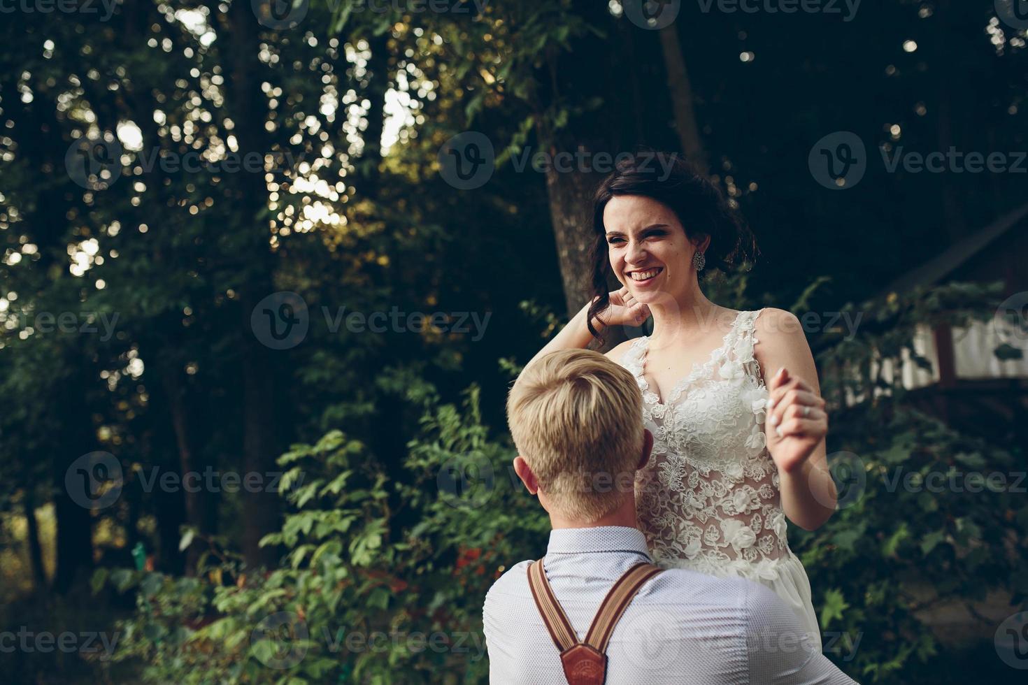 groom holds bride in his arms photo