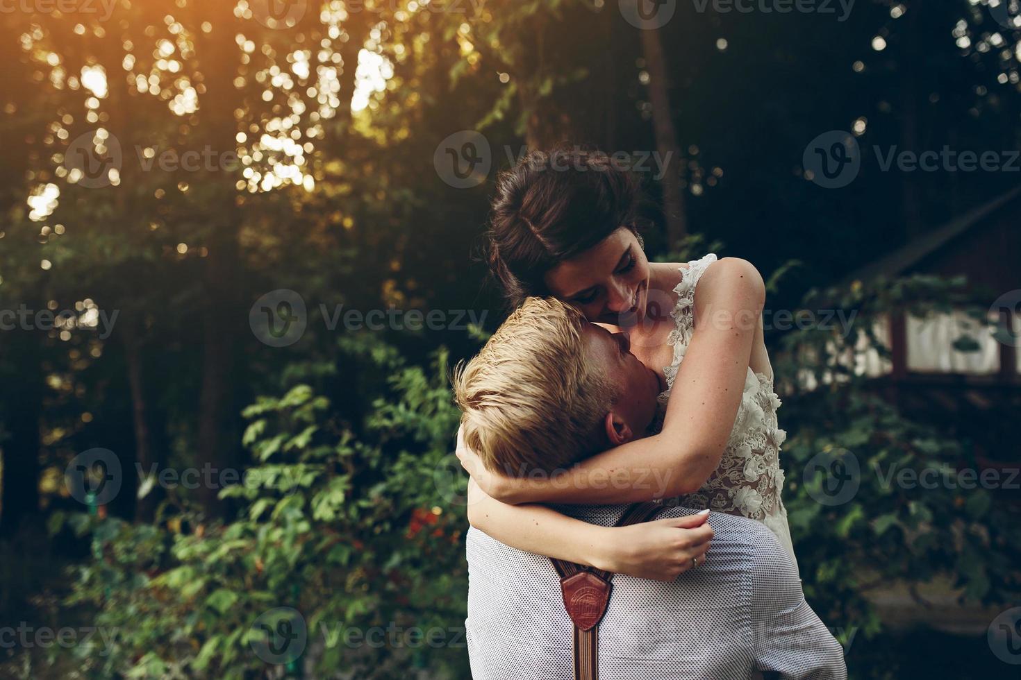 el novio sostiene a la novia en sus brazos foto