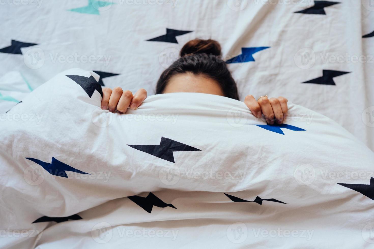 Closeup of Lovely young Woman Lies in Bed Covered with Blanket. photo