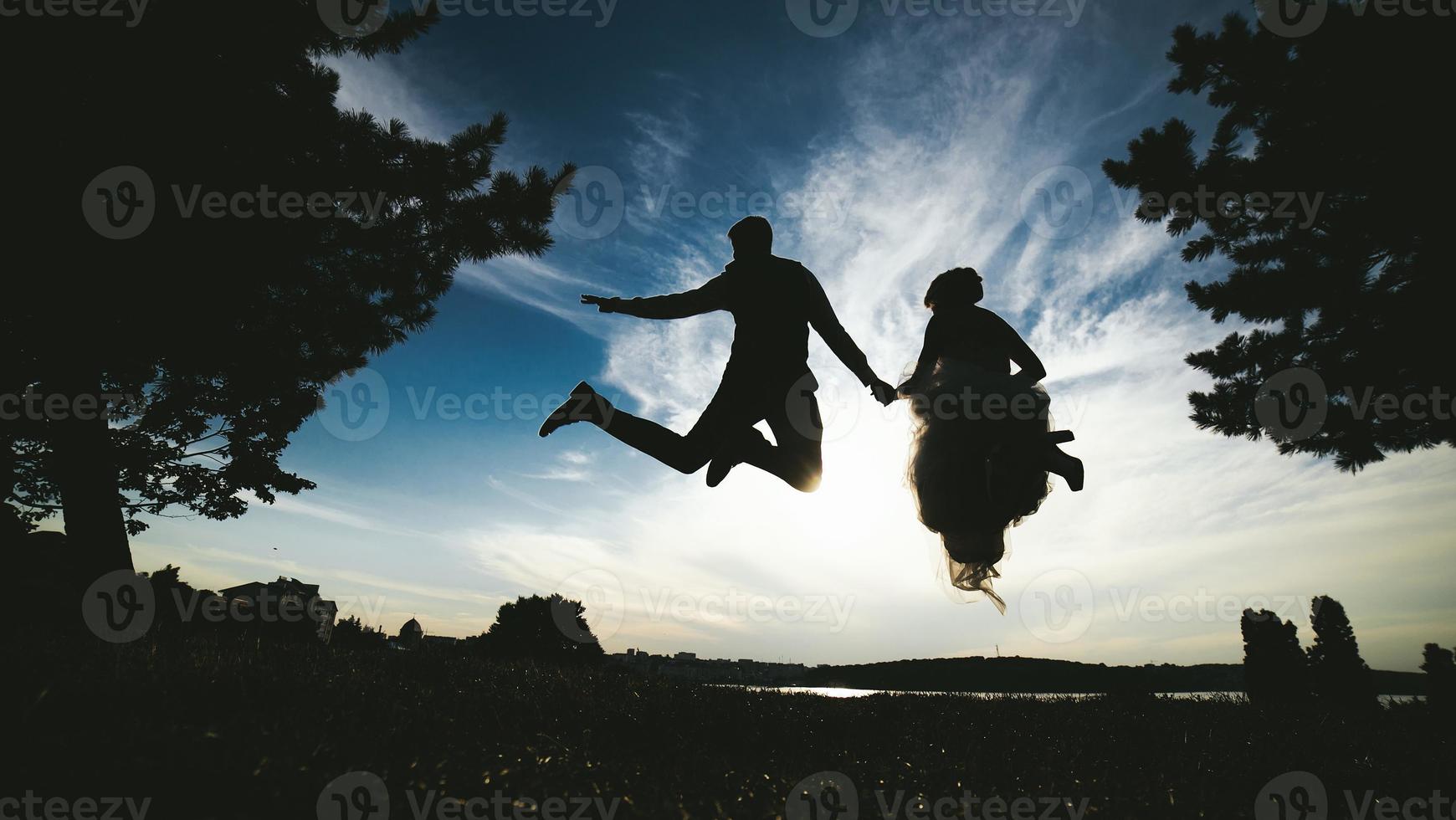 groom and bride jumping against the beautiful sky photo