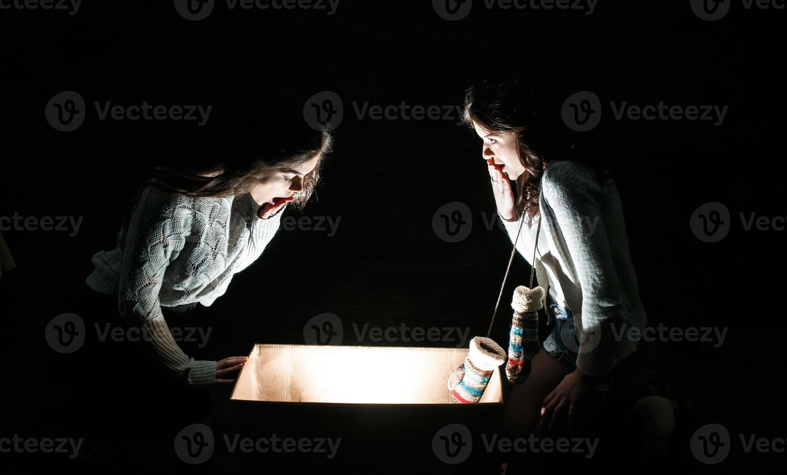 las hermanas abren una caja con un regalo de navidad y miran fascinadas dentro foto