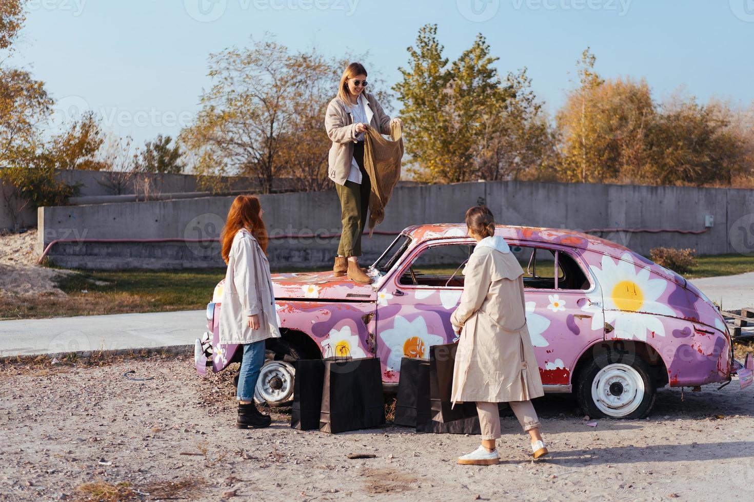 Young women posing near an old decorated car photo