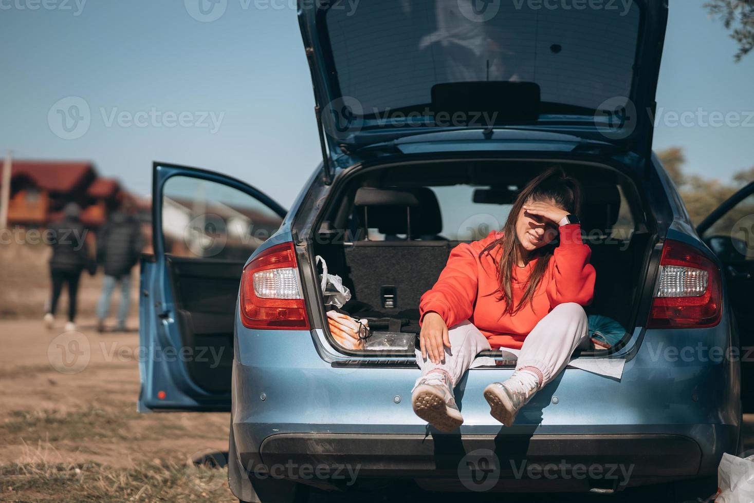 joven atractiva descansando en el maletero de un coche foto