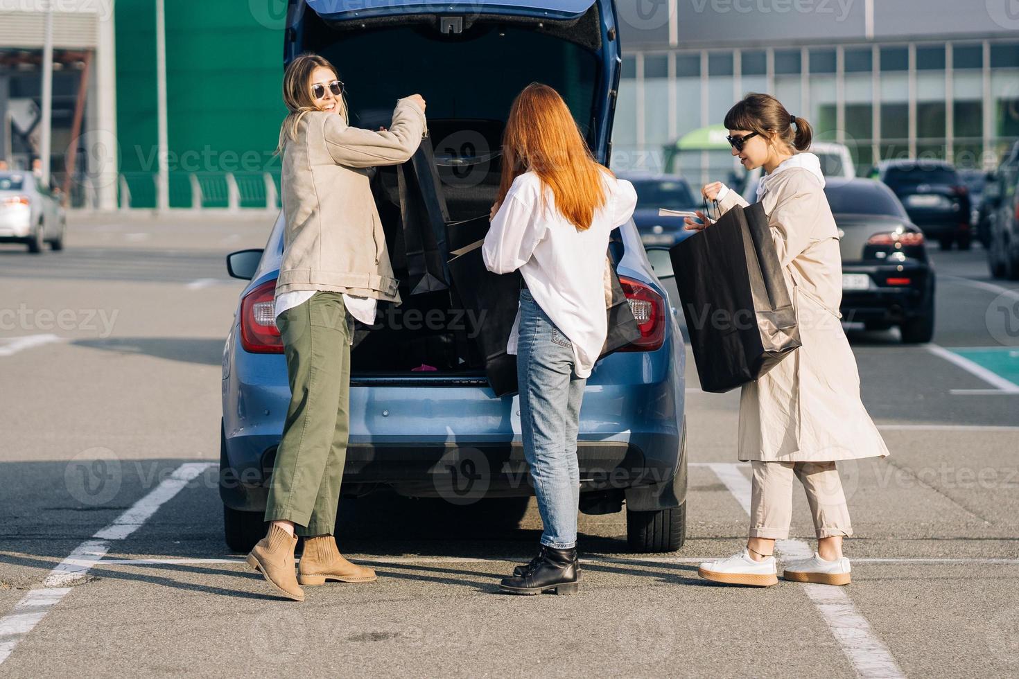 Young women at the car with shopping bags photo