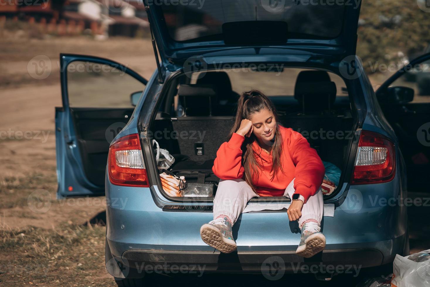 Attractive young woman resting in the trunk of a car photo