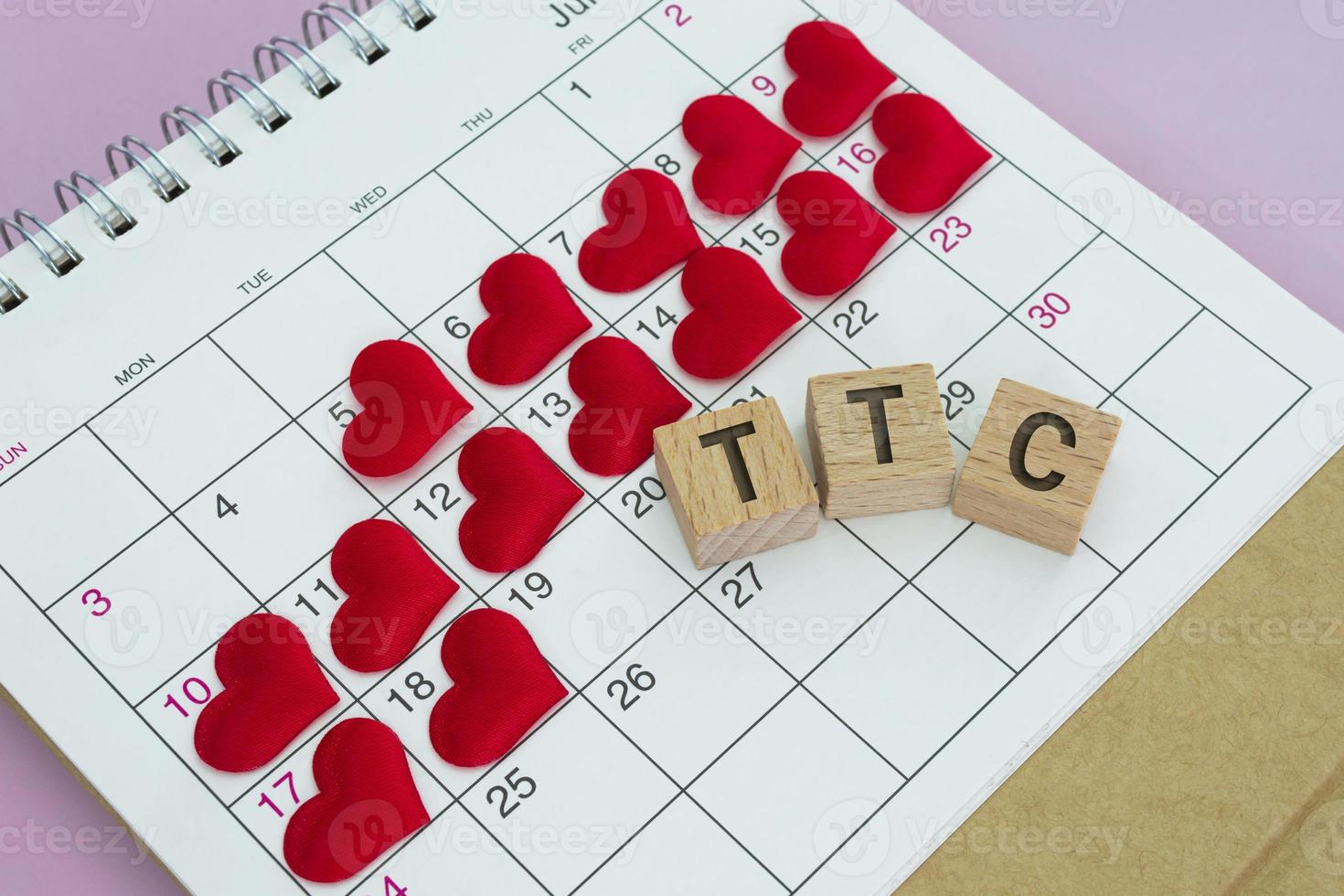 TTC word on wooden block with red heart shape on calendar. Trying To Conceive. photo