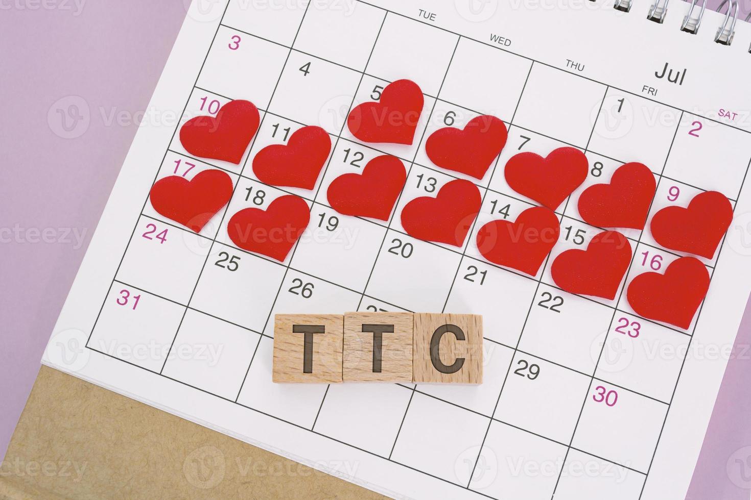 TTC word on wooden block with red heart shape on calendar. Trying To Conceive. photo