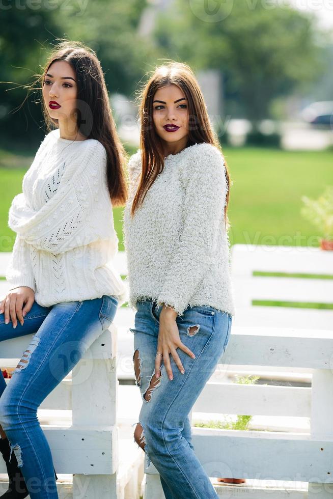 Two girls lean bench photo