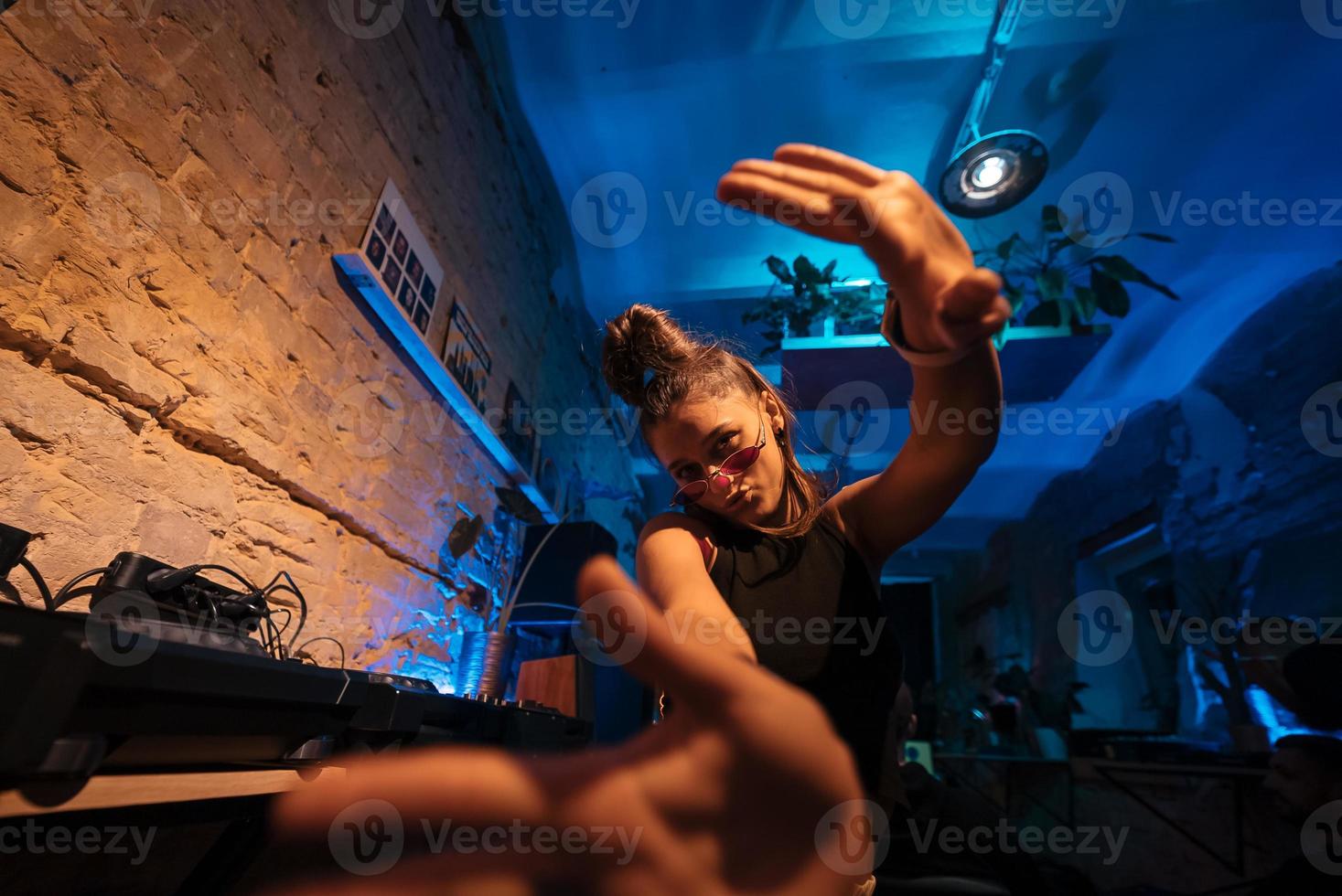 Beautiful female DJ dancing to techno in a small club photo