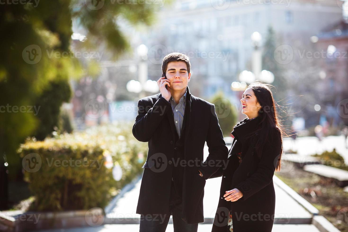 businessman talking on the phone while woman comes to him photo