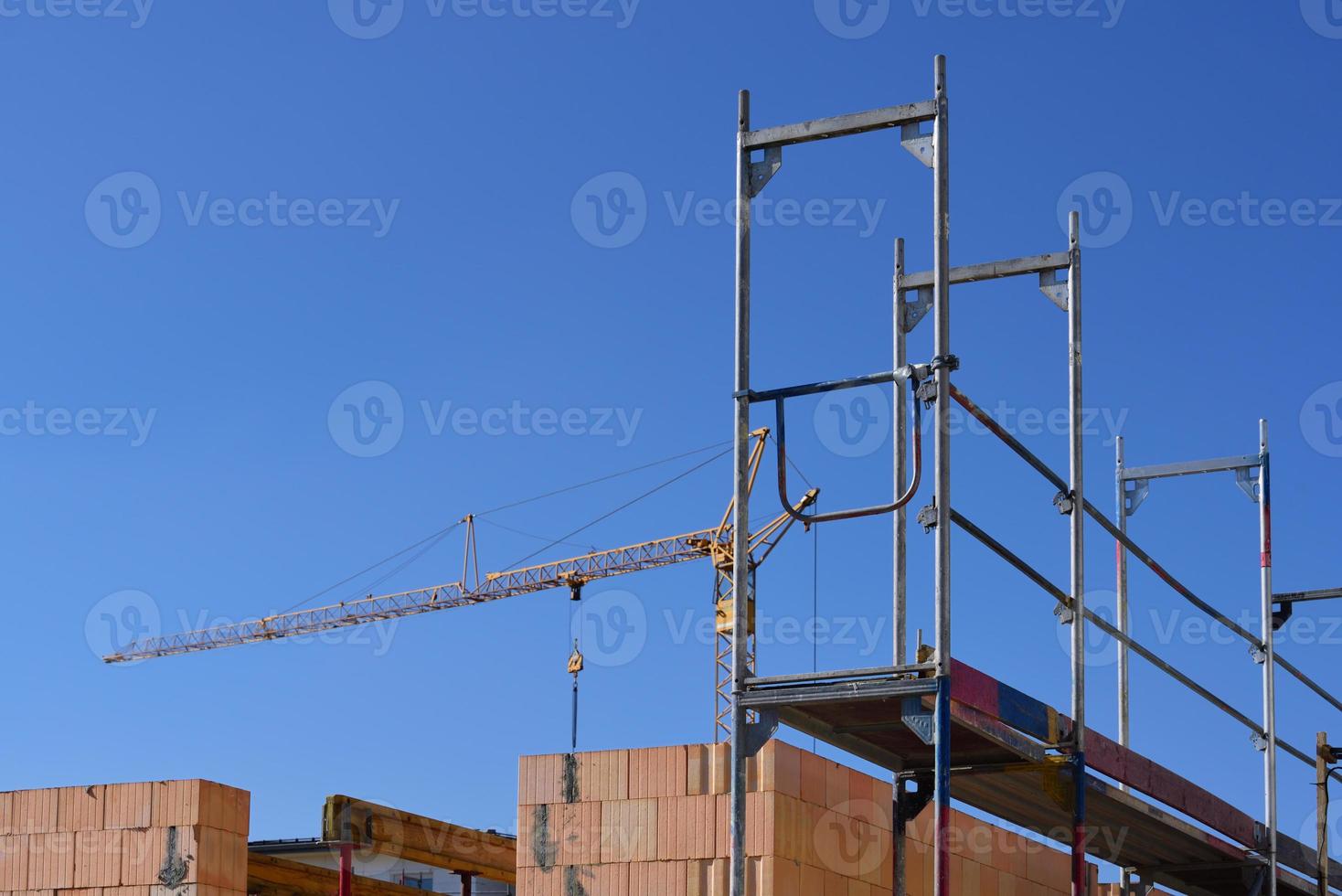 Close-up of a shell of a stone house with scaffolding, on a construction site for a residential area, against a blue sky photo