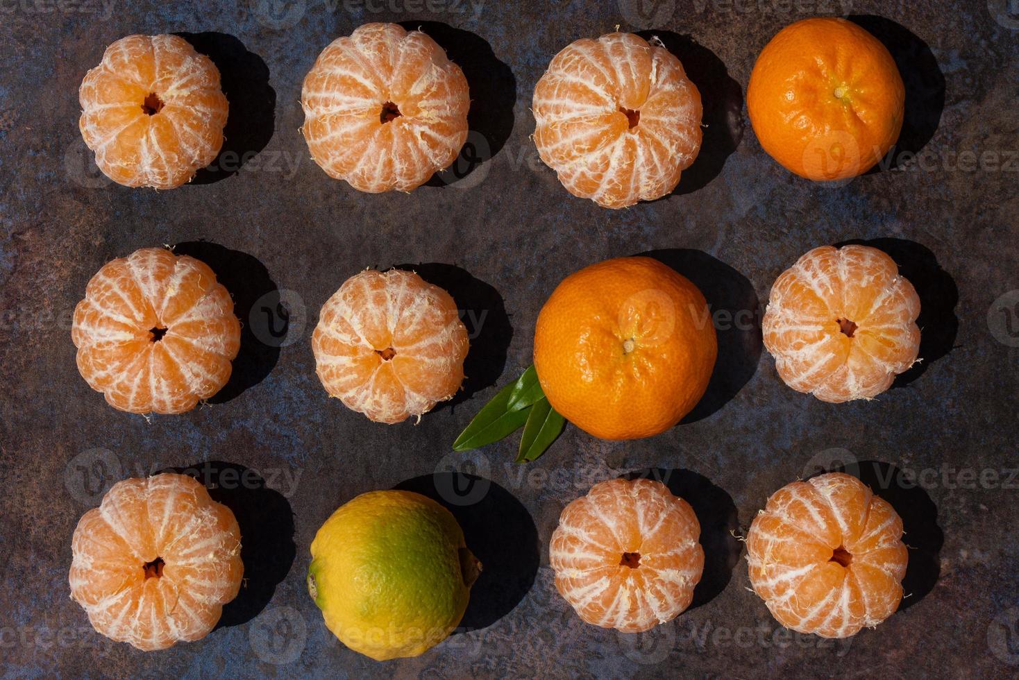 Several peeled and unpeeled mandarins lie next to each other on a marbled surface photo