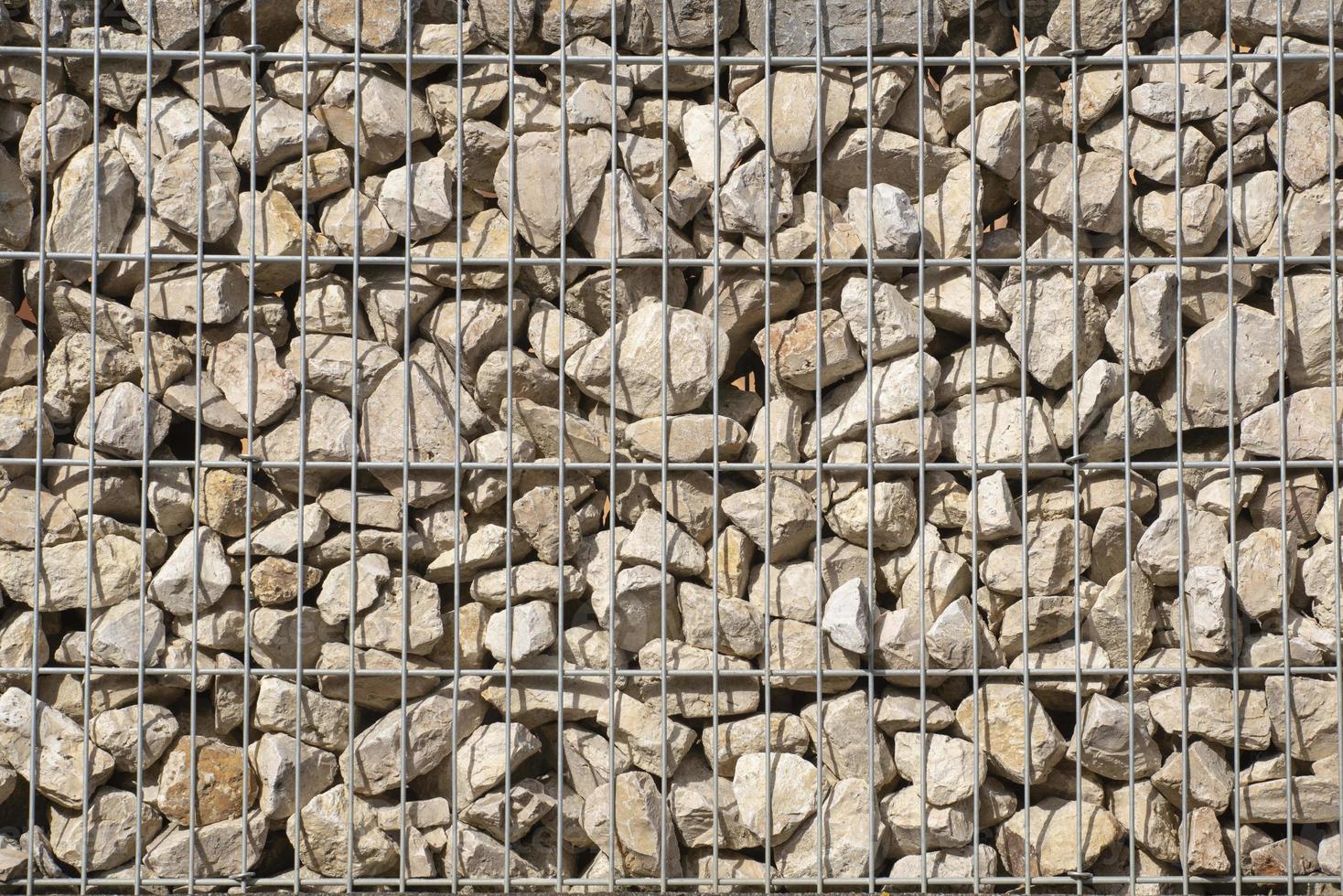Background and texture of many rough stones lying in a metal stone cage forming a wall photo