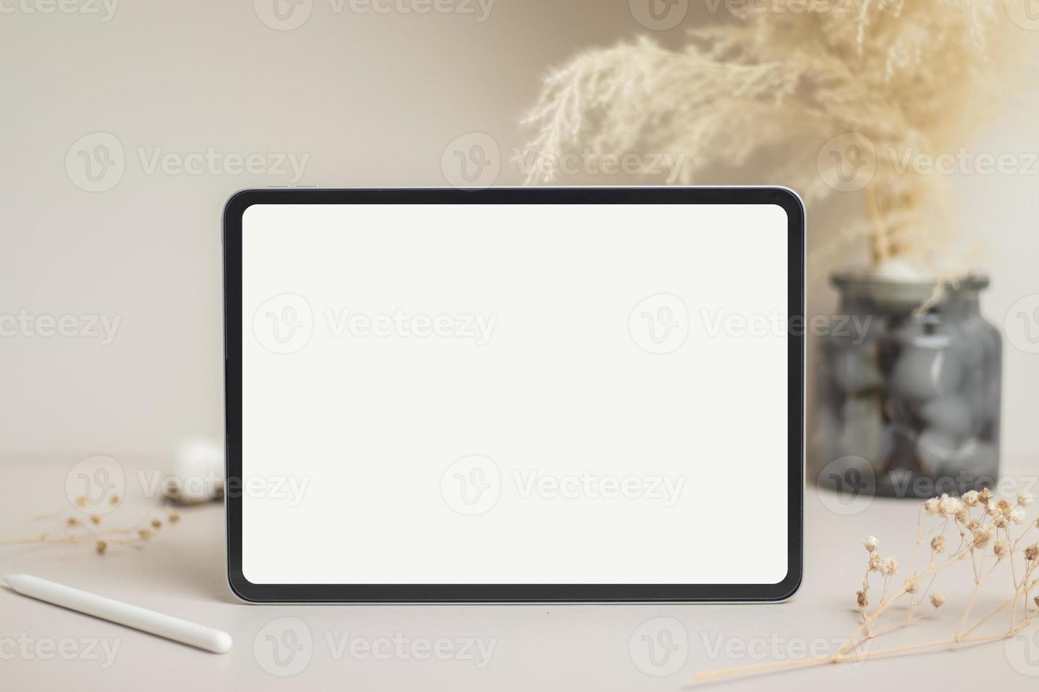 Tablet empty white screen with pencil mock-up. Cotton flower and dry leaves on beige background mockup for design photo