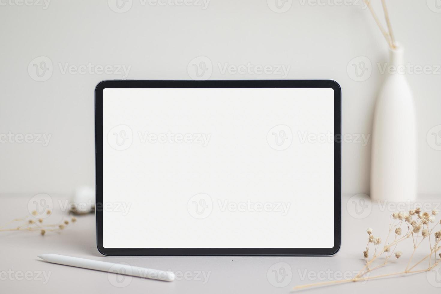 Tablet empty white screen with pencil mock-up. Cotton flower and dry leaves on beige background mockup for design photo