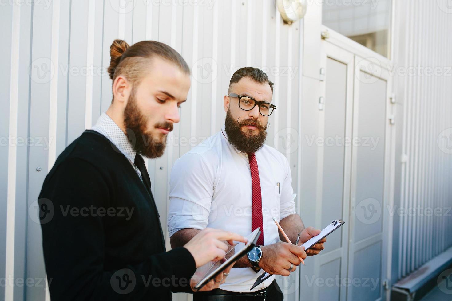 Two bearded businessman looking at something photo