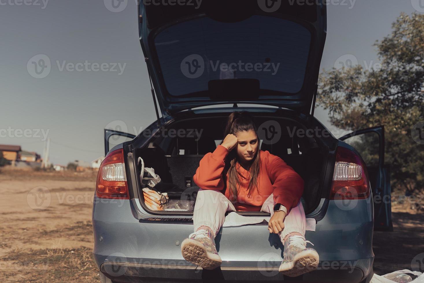 Attractive young woman resting in the trunk of a car photo