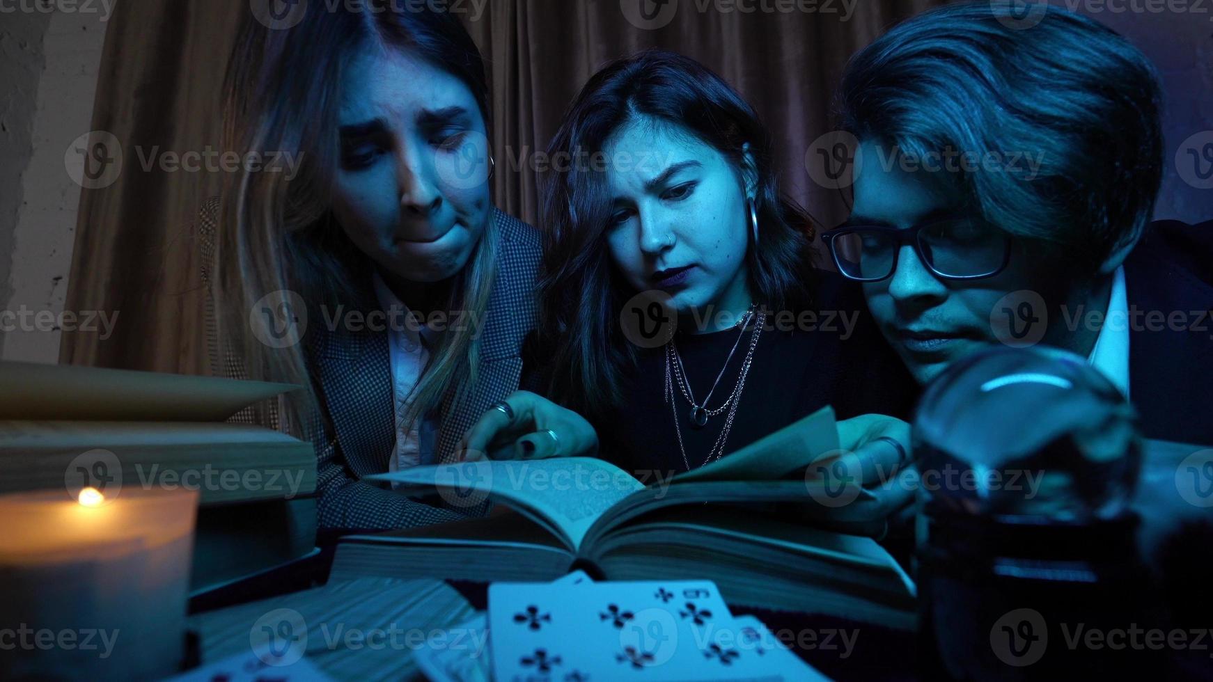 Two women and a guy are reading a mysterious books, close view photo