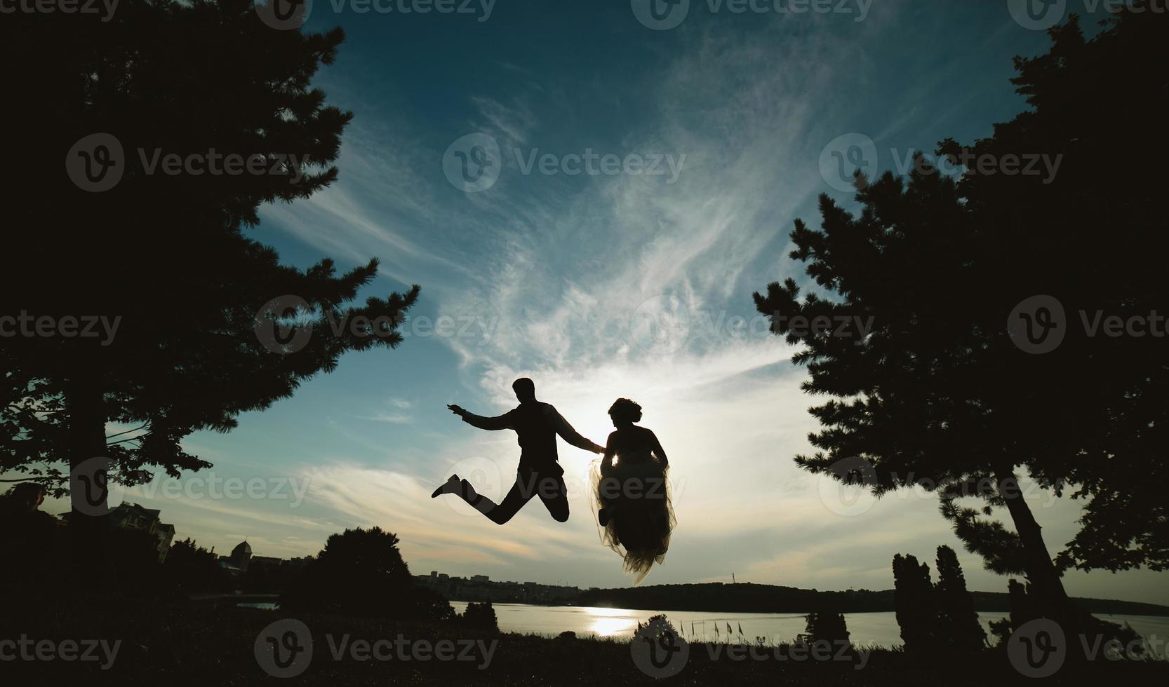 groom and bride jumping against the beautiful sky photo