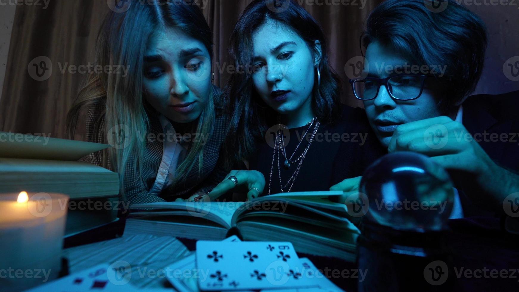 Two women and a guy are reading a mysterious books, close view photo