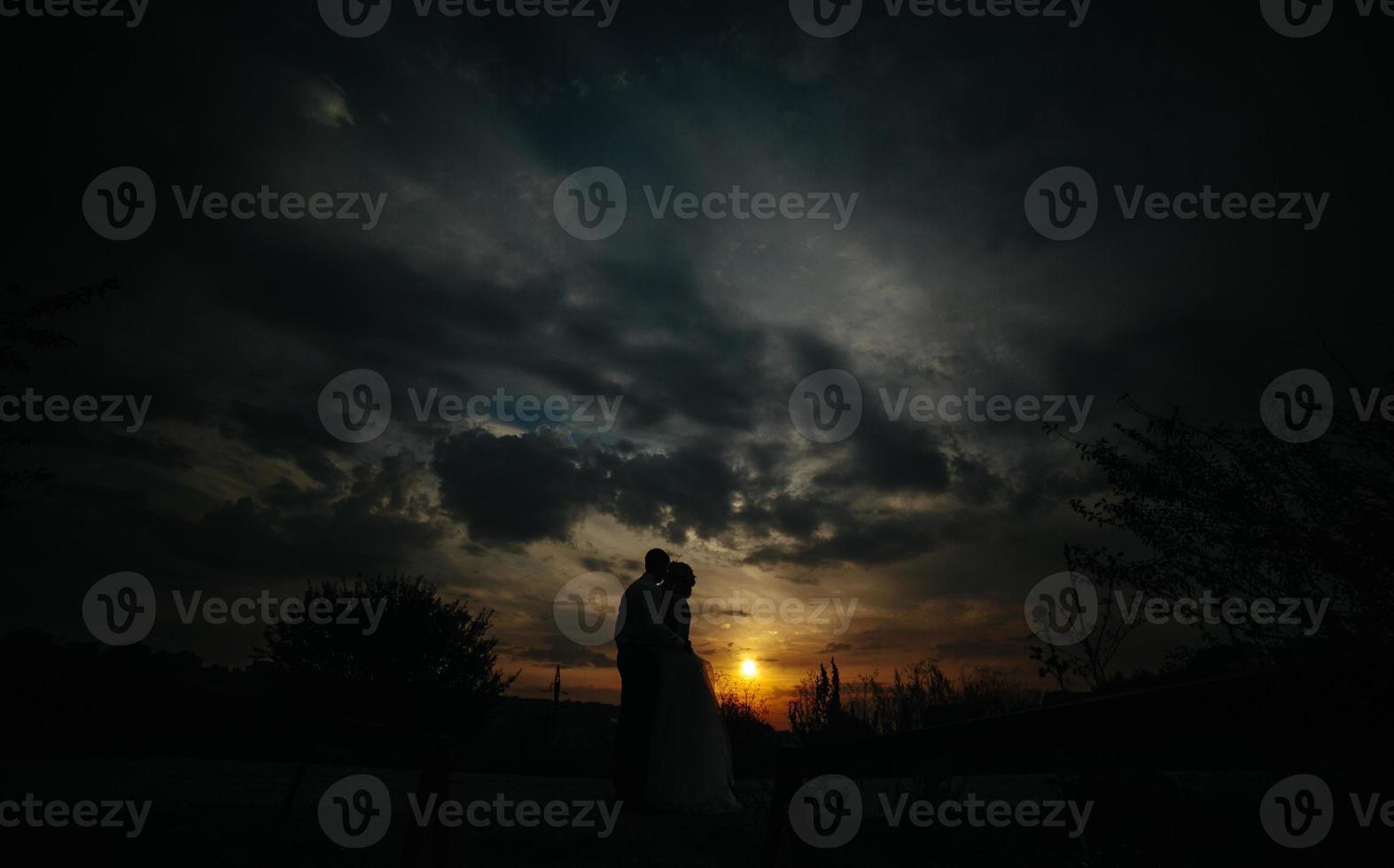 Silhouette of  wedding couple in field photo