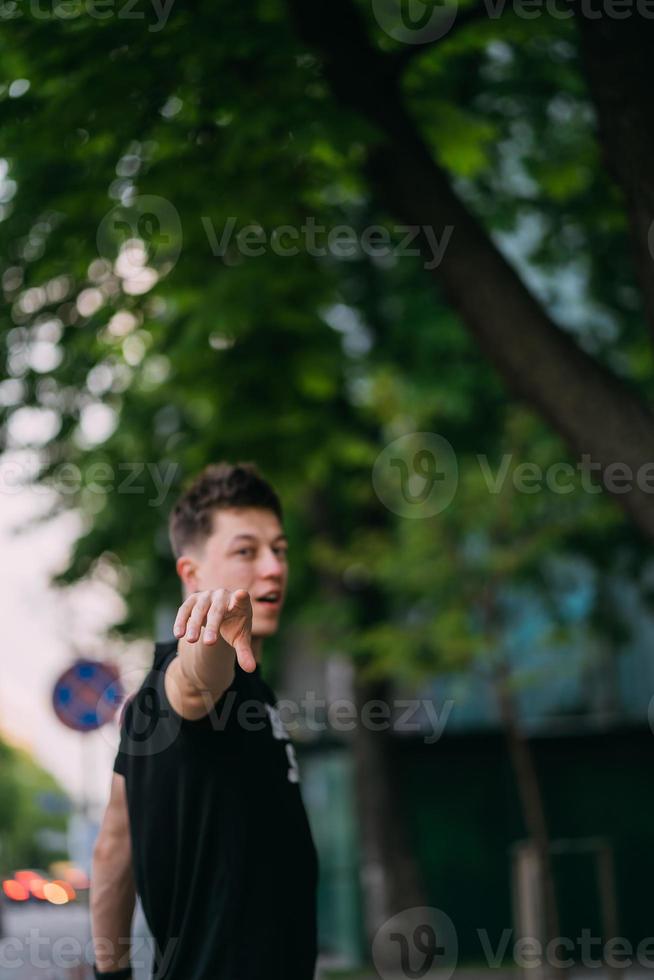 Young adult man in a black t-shirt and jeans walks on a city street photo