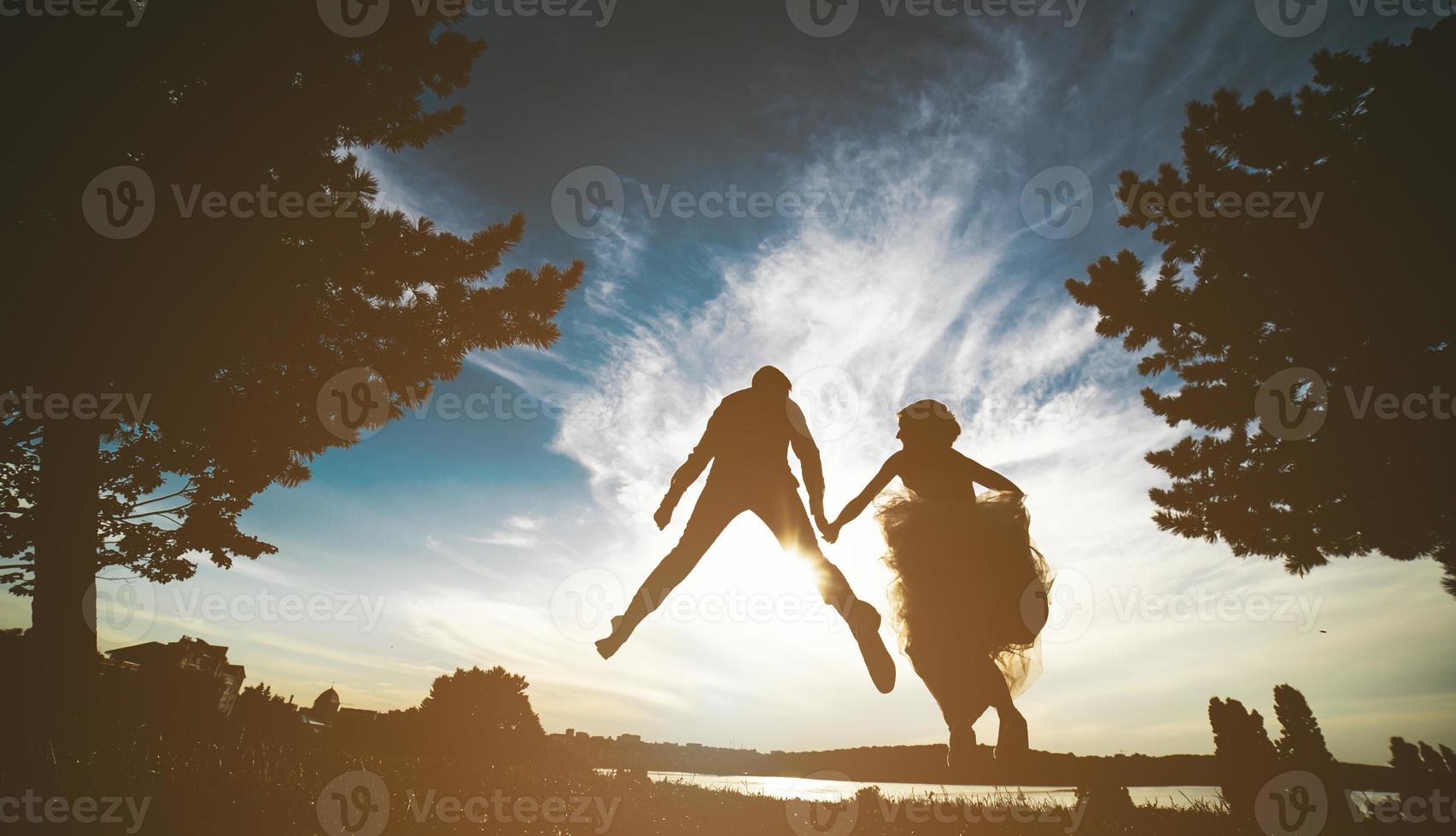 groom and bride jumping against the beautiful sky photo