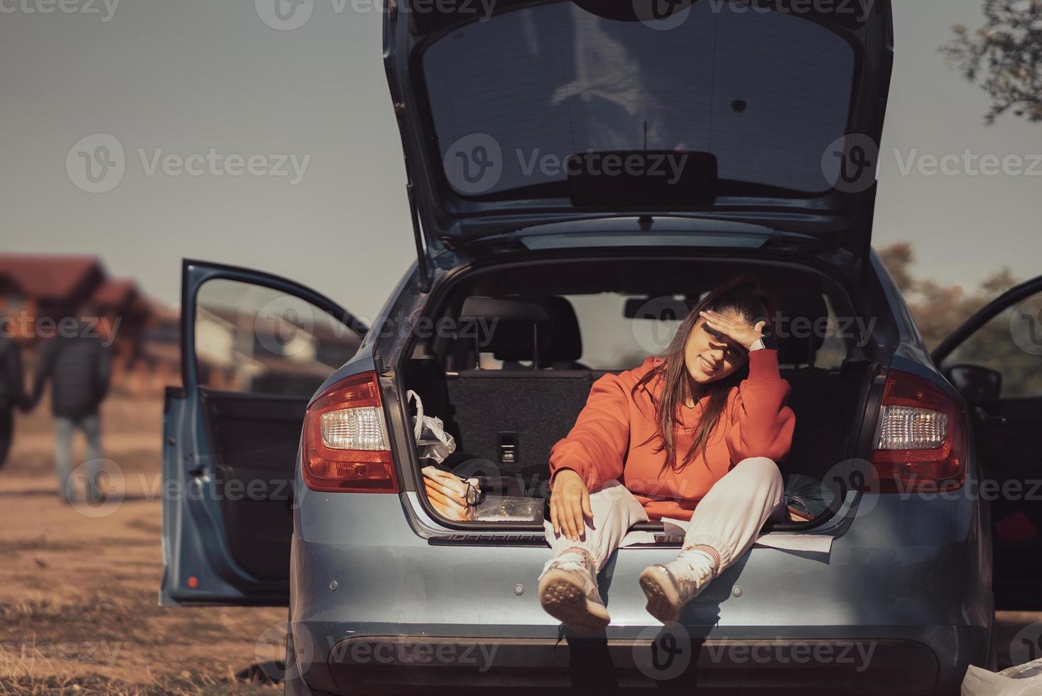 joven atractiva descansando en el maletero de un coche foto